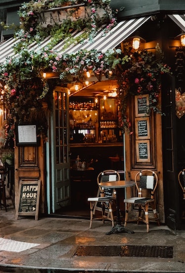 Cozy cafe in France with doors open and a table with chairs out front.