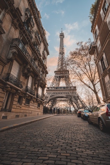 Photo of a cbblestone street and buildings with low-angle shot of the Eiffel Tower in the middle