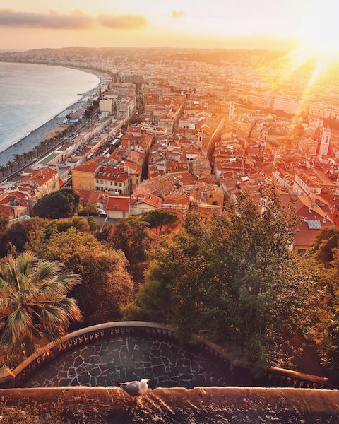 Ariel view of the city of Nice at sunset with buildings on the right and the beach on the left.
