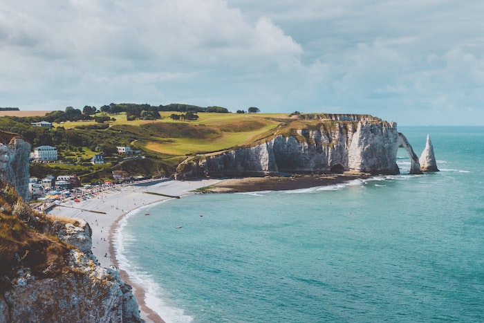 Rolling hills in Normandy with the ocean to the right under a gray, cloudy sky.