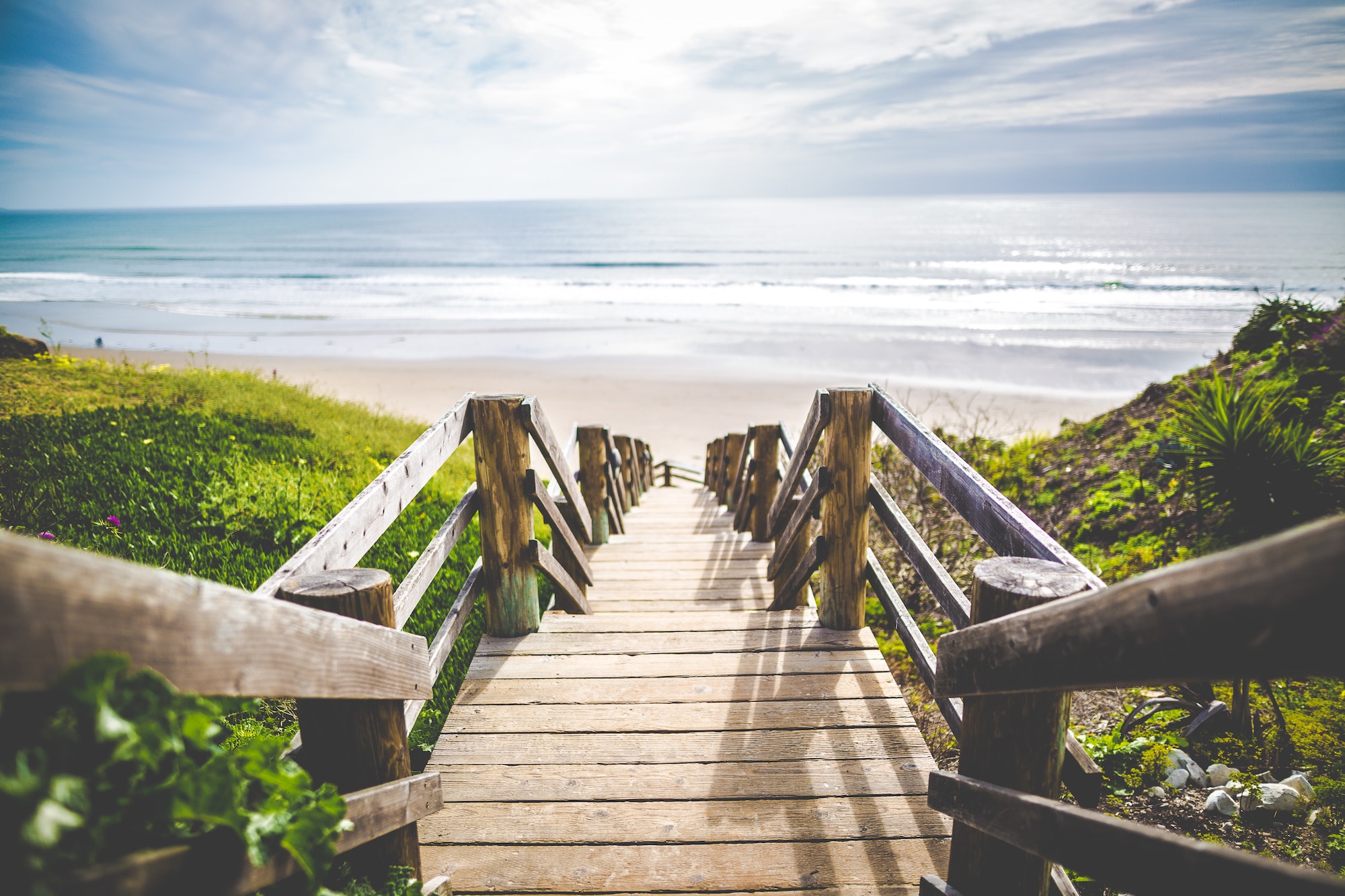 Wooden stairs leading down to sand and water at the beach